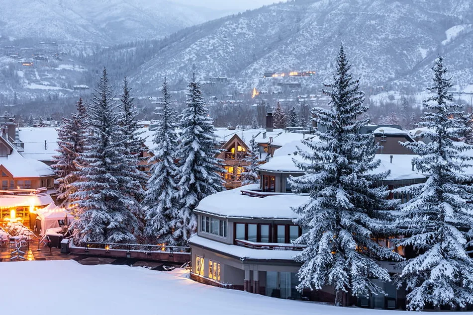 Dusk in the snow at the base of Aspen Mountain, lights on in the village